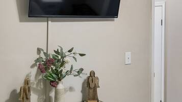 A flat-screen TV mounted on a wall above a wooden console with drawers and decorative items.