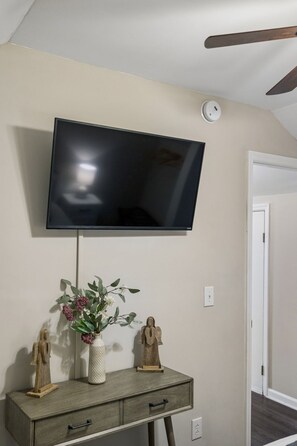 A flat-screen TV mounted on a wall above a wooden console with drawers and decorative items.