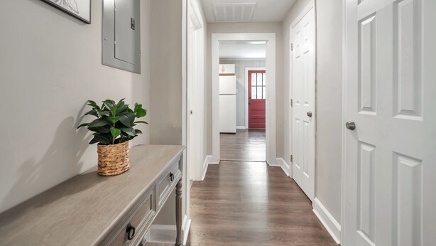 A hallway with a wooden floor, white walls, and a door at the end. - Cute Modern Townhouse Close to MTSU, Parks & Downtown: Large Master & Coffee Bar (Murfreesboro)