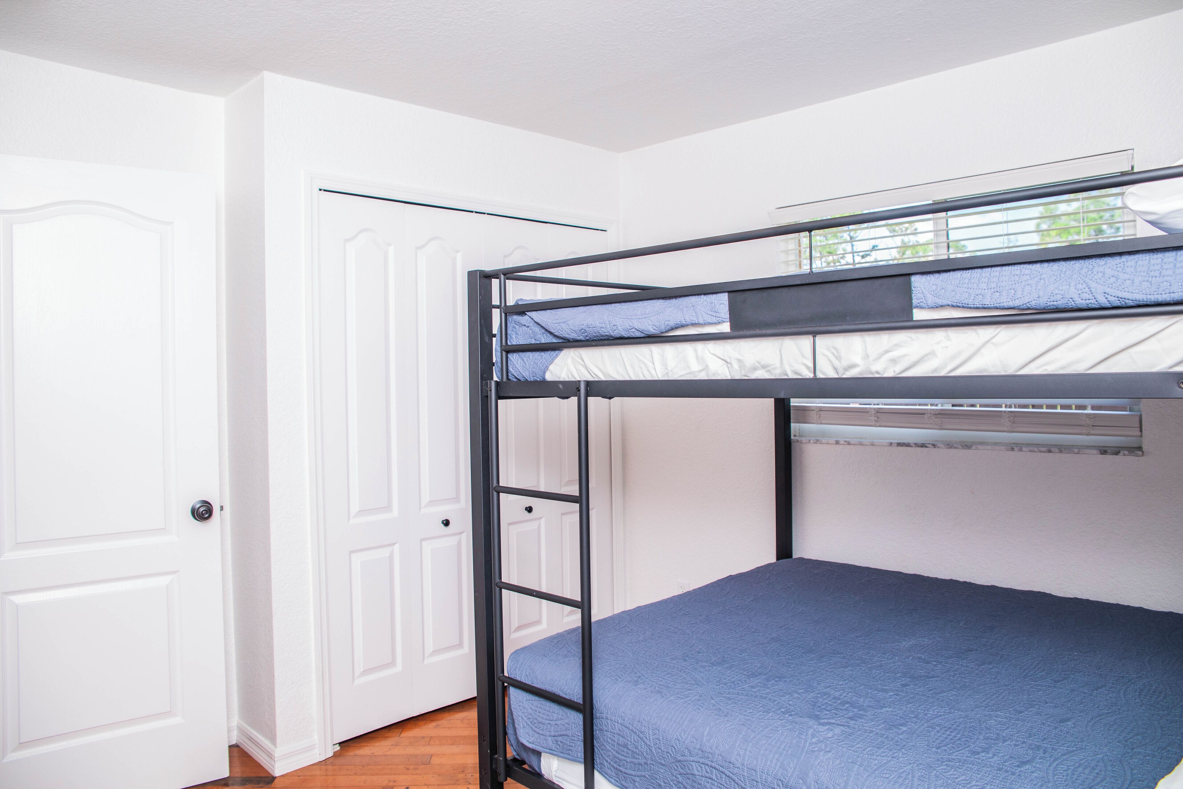 A bunk bed with a ladder, white walls, and a door.
