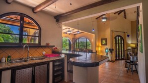 A kitchen with a large island, a window, and a view of the outdoors. - Casa Paraiso - Tropical Private Pool Near Beach (Esterillos Oeste)