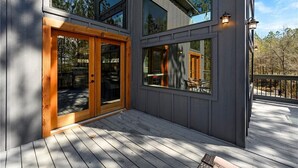 A modern building with large windows and a wooden deck. - Amazing Outdoor Area:  Pool Table, Hot Tub, Close to Attractions!  (Broken Bow)