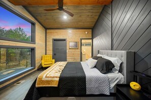 A modern bedroom with a large bed, a ceiling fan, and a view of the outdoors. - Amazing Outdoor Area:  Pool Table, Hot Tub, Close to Attractions!  (Broken Bow)