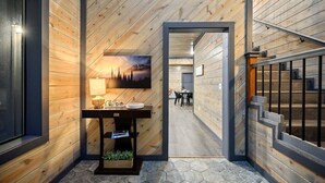 A wooden interior hallway with a table, a painting, and a staircase. - Amazing Outdoor Area:  Pool Table, Hot Tub, Close to Attractions!  (Broken Bow)