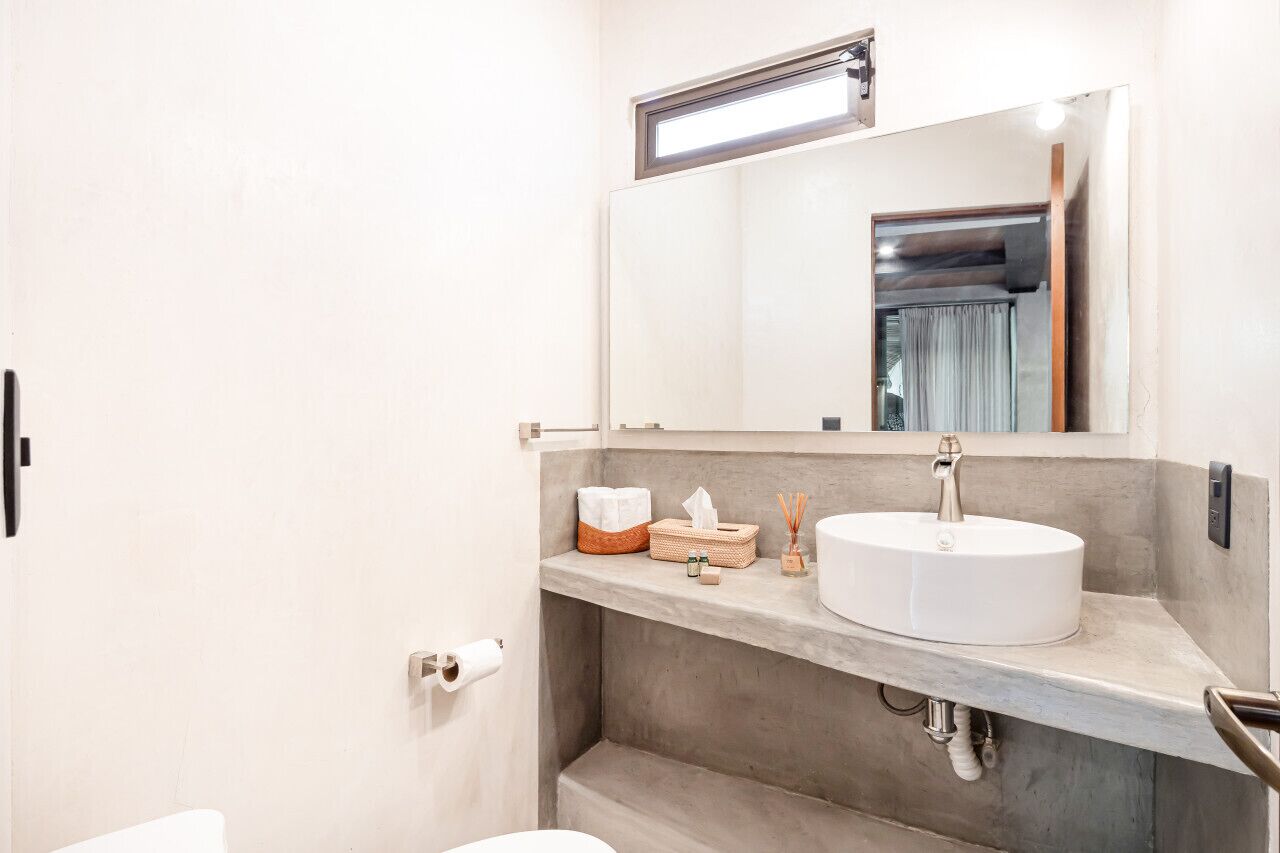 A modern bathroom with a white sink, a mirror, and a towel rack.