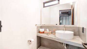 A modern bathroom with a white sink, a mirror, and a towel rack.