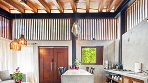 Cocina moderna con una isla central, vigas de madera en el techo y vistas a zonas verdes.