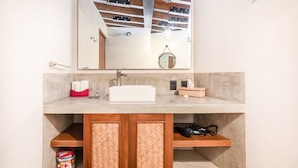 Un baño con un mueble de madera, un lavabo blanco y un espejo encima.