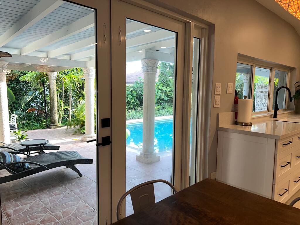 A modern kitchen with a view of a swimming pool and outdoor seating area.