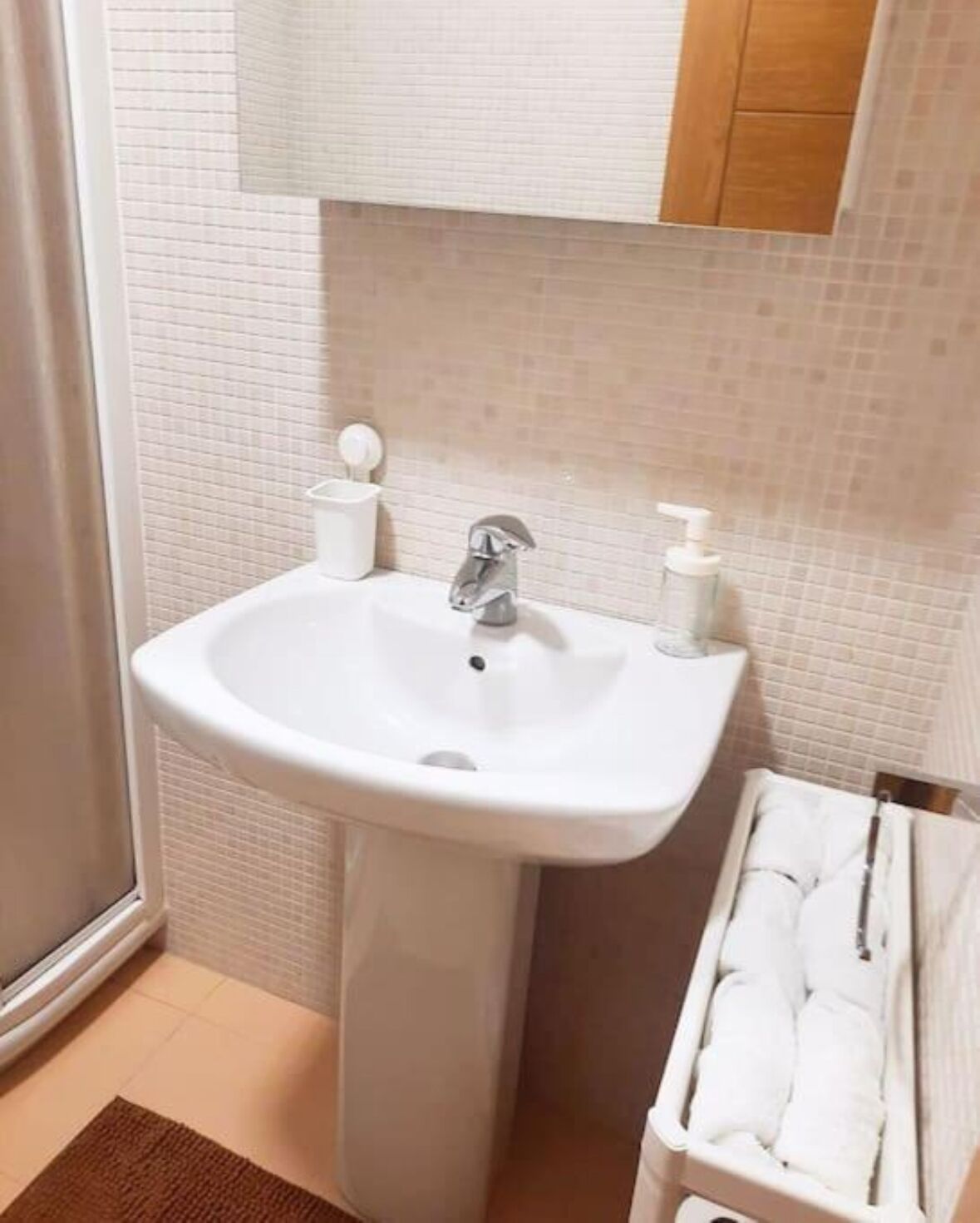 A bathroom with a white sink, a mirror, and a towel rack.
