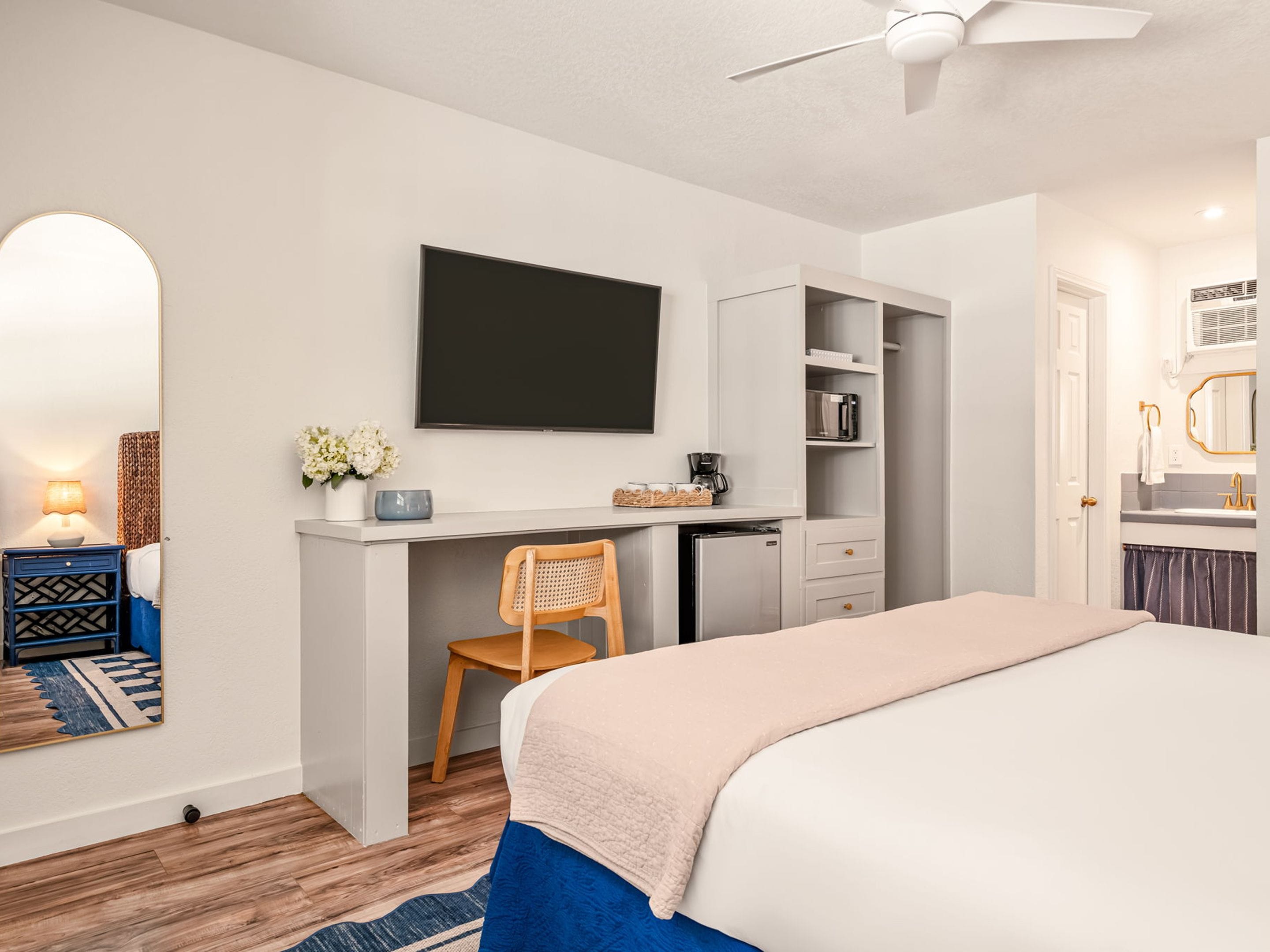 Un dormitorio con cama, escritorio, silla, televisor y armario.