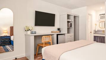 Un dormitorio con cama, escritorio, silla, televisor y armario.