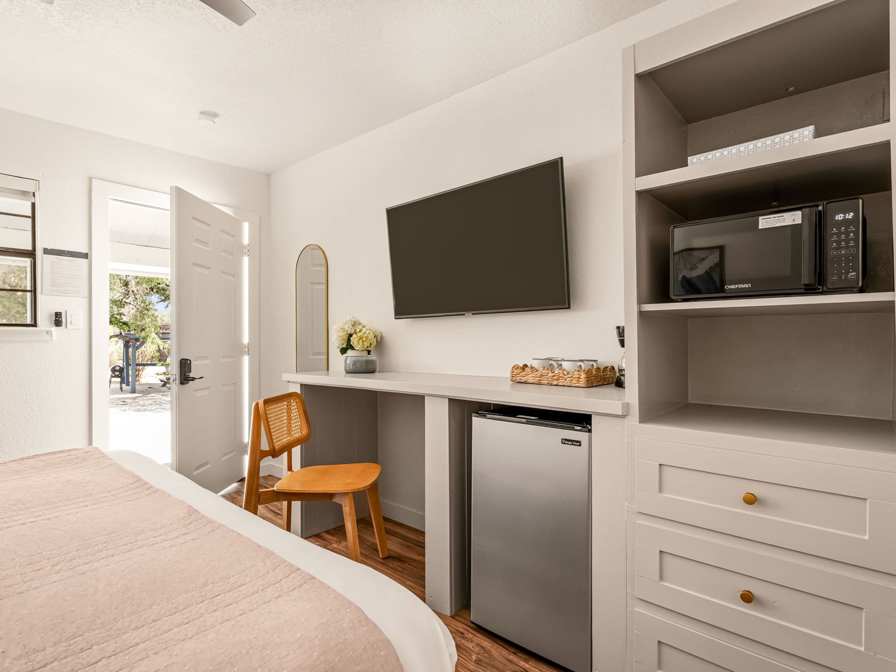 Habitación compacta con cama, escritorio, televisor de pantalla plana, microondas y lavavajillas pequeño.