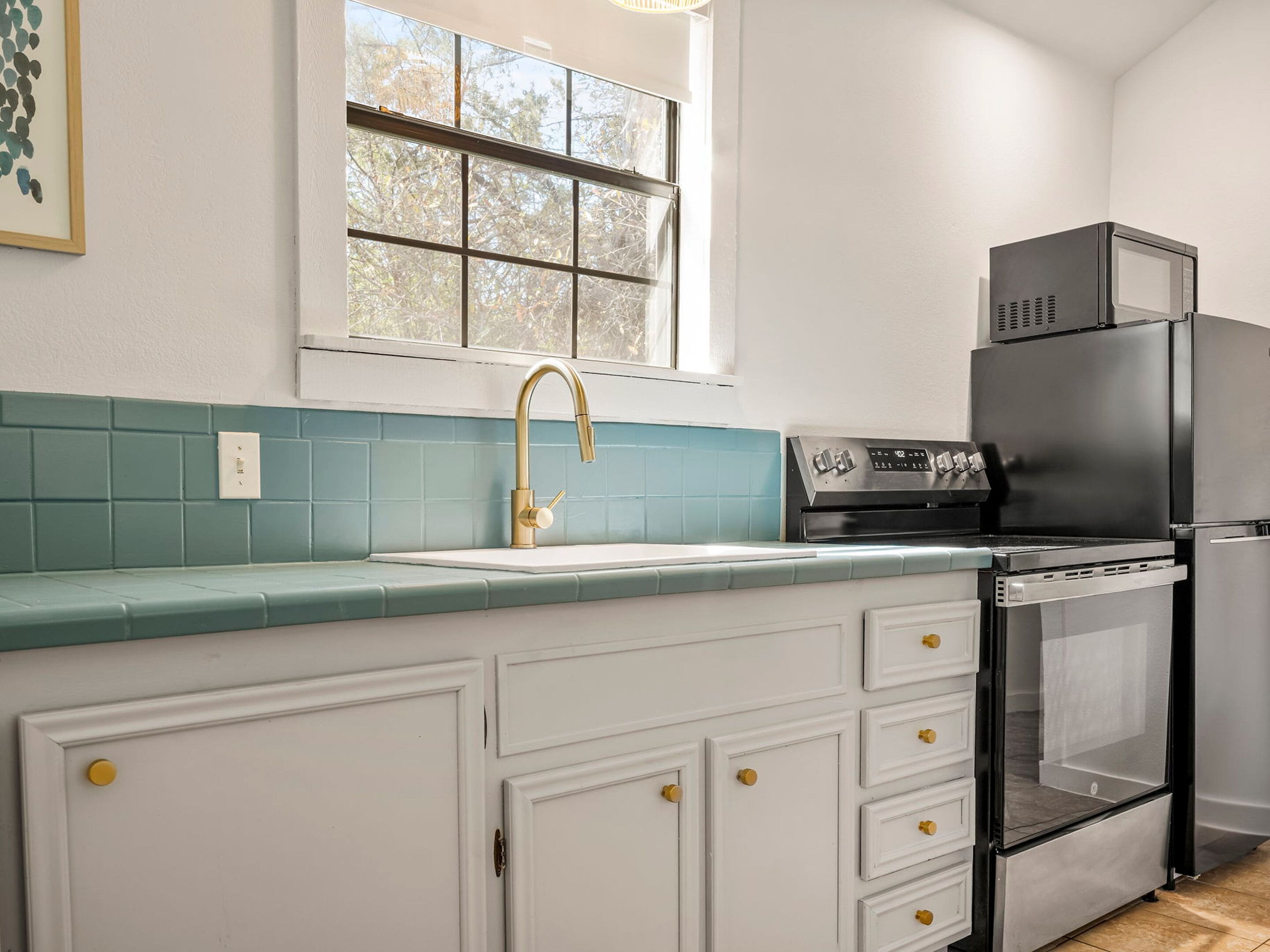 A kitchen with a window, a sink, a stove, and a refrigerator.