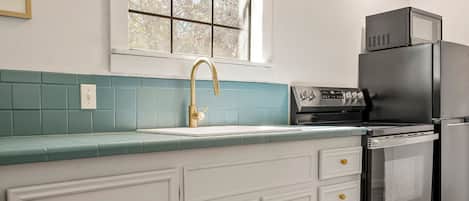 A kitchen with a window, a sink, a stove, and a refrigerator.
