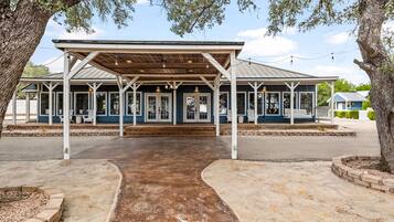 A covered outdoor area with a concrete pathway leading to a building with multiple doors and windows.