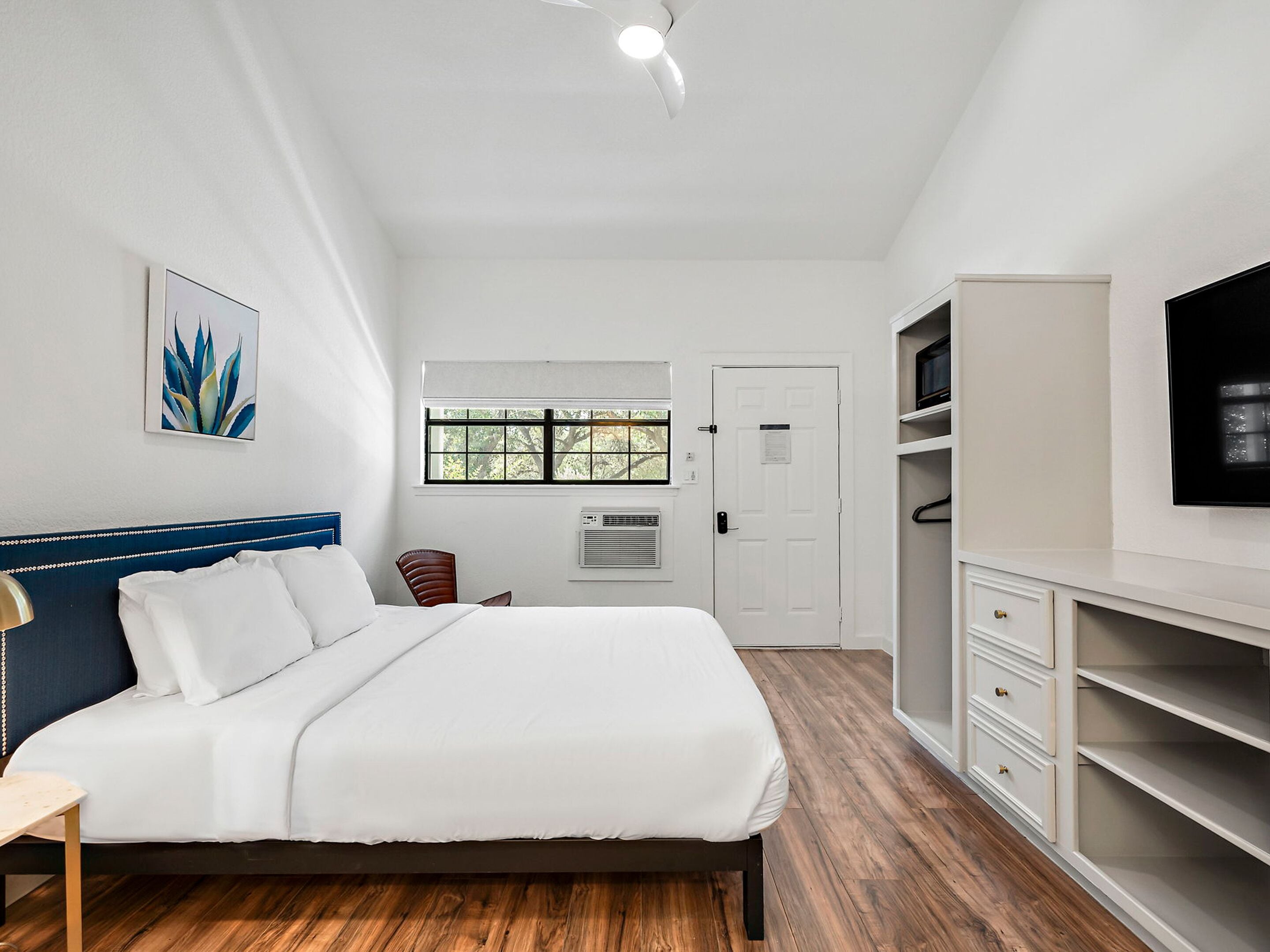 A bedroom with a bed, a desk, a chair, a TV, and a wardrobe.