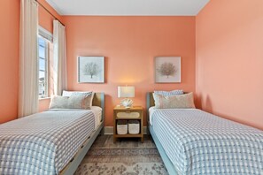 Habitación de hotel con dos camas, una mesita de noche con lámpara y dos cuadros en la pared.