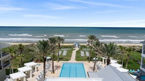 A resort with a swimming pool, beach view, palm trees, and lounge chairs. - New Beachcombers @ Luxurious Cinnamon Cove w/ Pool (Palm Coast)