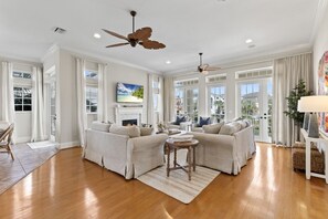 A spacious living room with a fireplace, comfortable seating, and large windows. - New Beachcombers @ Luxurious Cinnamon Cove w/ Pool (Palm Coast)