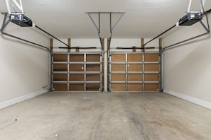 Un garage avec deux portes métalliques, un sol en béton et un éclairage au plafond.