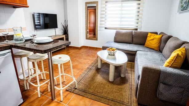 Una cocina moderna con televisor, taburetes de bar y una mesa de comedor.