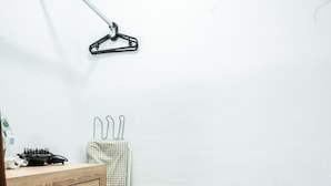 Una habitación pequeña y ordenada con un aparador de madera, un mueble negro y un tendedero a cuadros adosado a la pared.