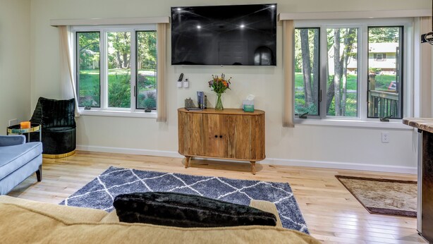 Una sala de estar con un televisor de pantalla plana colocado sobre un mueble de madera, un sofá azul y una alfombra estampada.