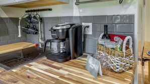 Una cocina con cafetera, un lavabo y una cesta de pan.