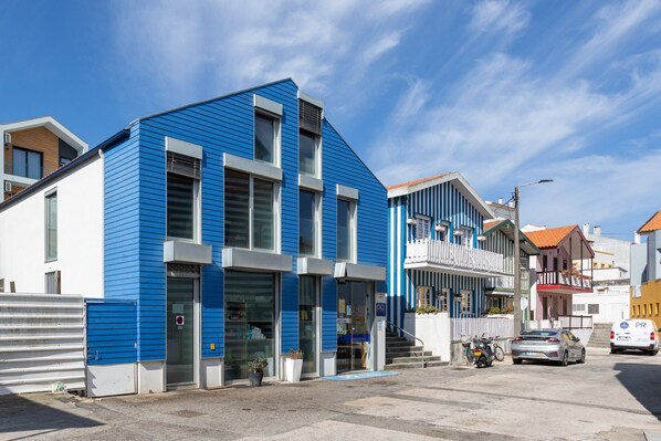 Ein modernes Gebäude mit blauer Fassade, großen Fenstern und einer sichtbaren Schaufensterfront.