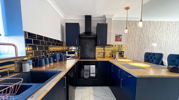 A modern kitchen with a central island, black cabinets, and a marble backsplash. - Lock View (Boston)