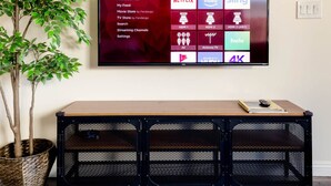 Un televisor de pantalla plana montado en la pared, mostrando diversas opciones de servicios de transmisión y configuraciones.