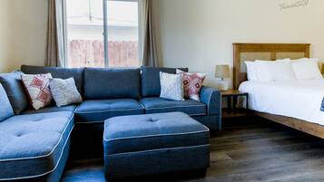 Una habitación de hotel moderna con sofá modular, cama y piso de madera.