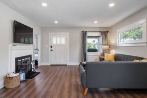Relax in this stylish living room with a large sofa, flat-screen TV, and cozy fireplace.