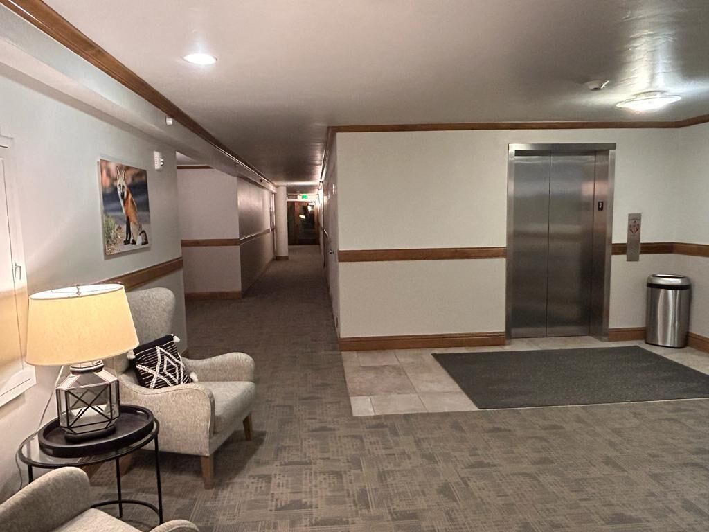 Eine Hotte Lobby mit einer Rezeption, einer Couch, einer Lampe, einem Gemälde, einem Aufzug und einem Mülleimer.