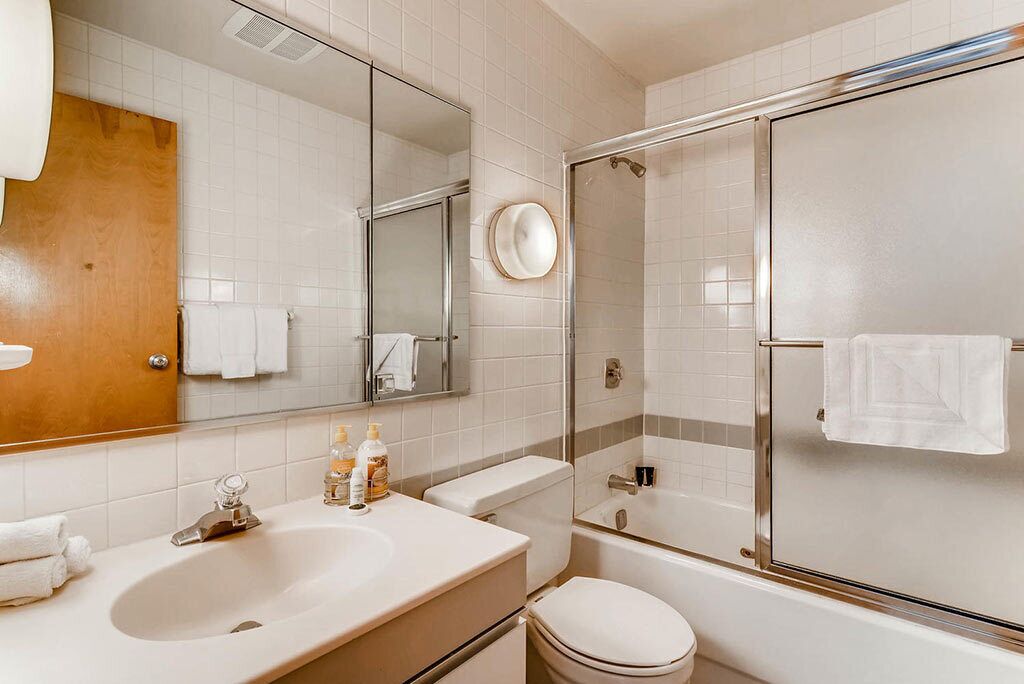 Une salle de bain moderne équipée d’un lavabo, d’un miroir, de toilettes et d’une douche.