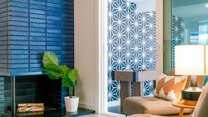 A modern living room with a fireplace, a potted plant, a sofa, and a patterned wall.