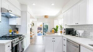 A modern kitchen with white cabinets, a gas stove, and a coffee maker.