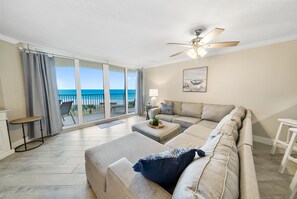 A living room with a large window, a ceiling fan, and a view of the beach.