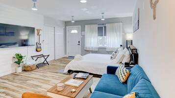 Un salon moderne et bien éclairé, avec un canapé bleu, une table basse en bois et un téléviseur fixé au mur.