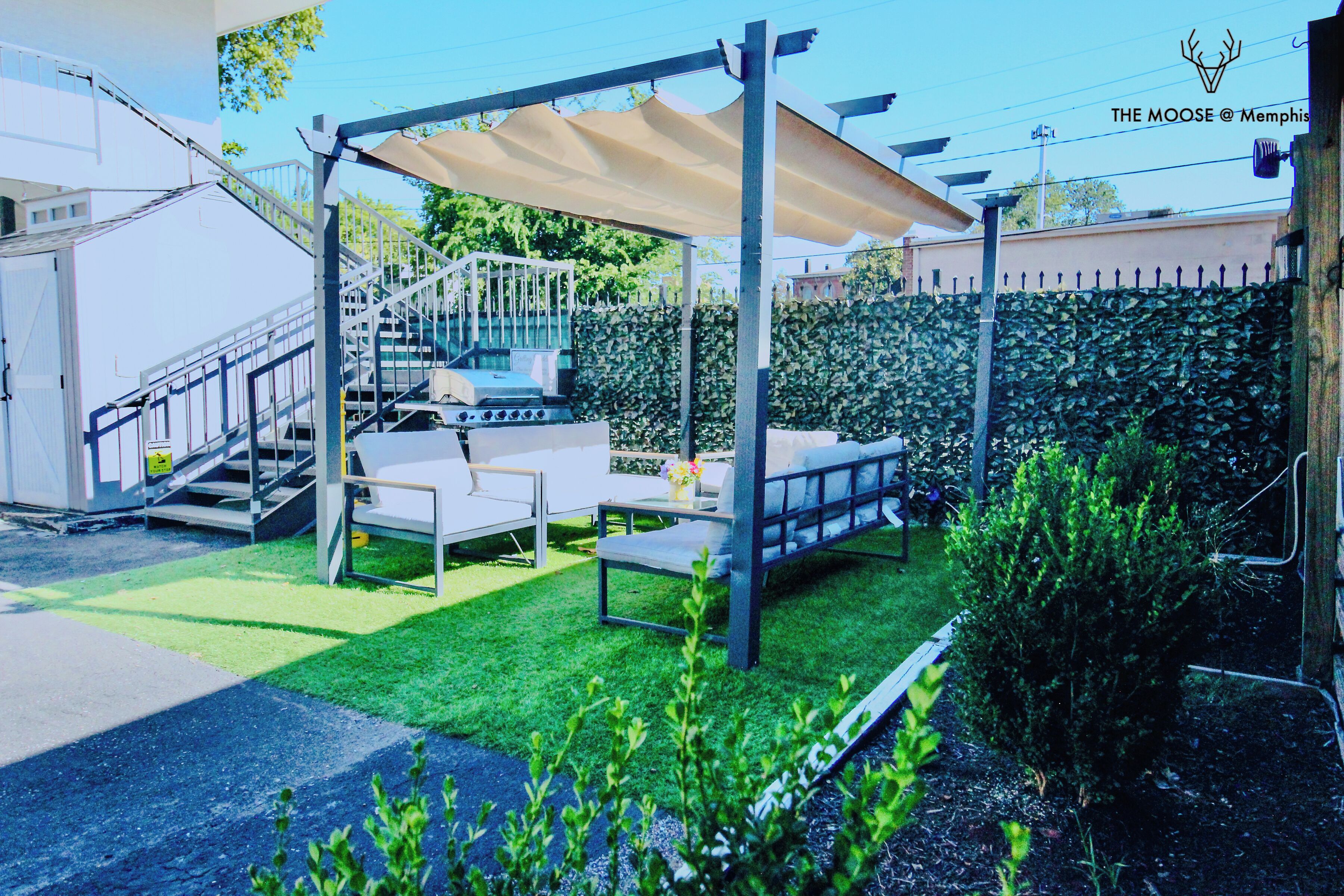 A patio area with a grill, outdoor seating, and a covered area.