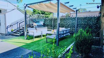 A patio area with a grill, outdoor seating, and a covered area.