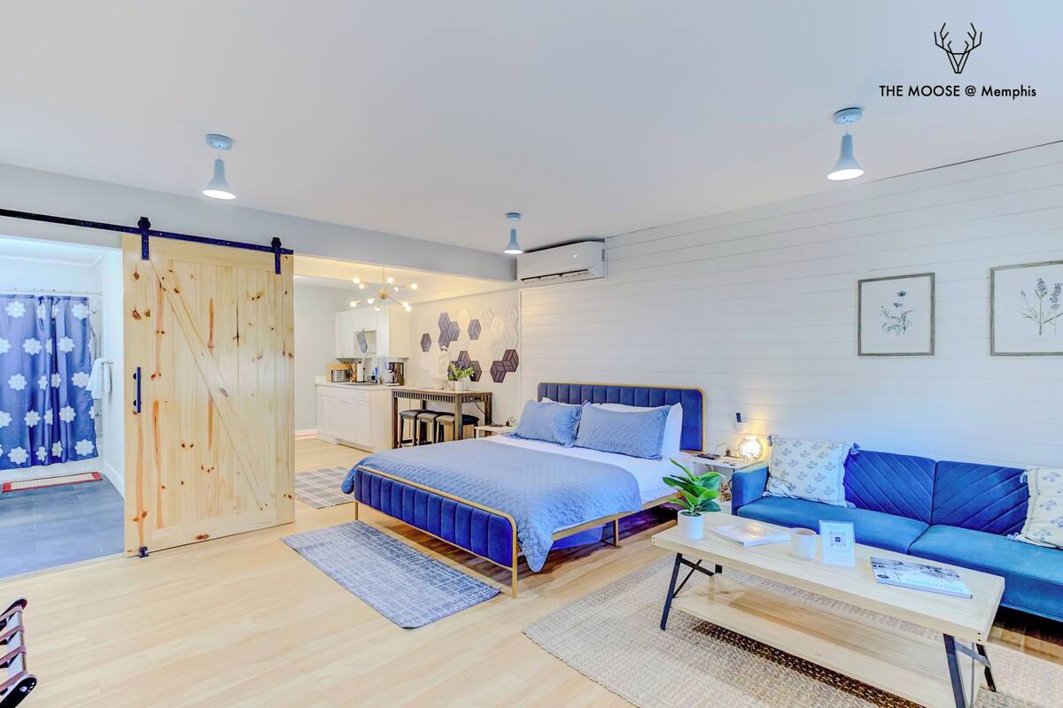 Un dormitorio moderno con cama, sofá azul, escritorio y puerta corredera.