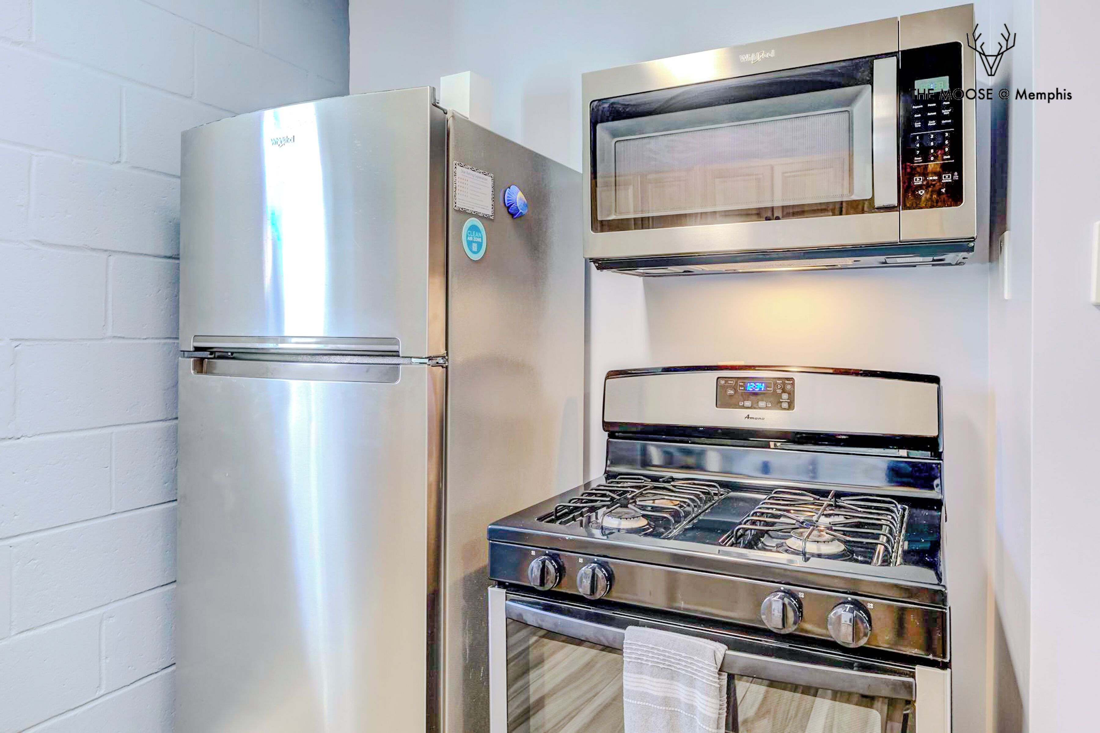 A kitchen with a stainless steel refrigerator, a microwave, and a gas stove.