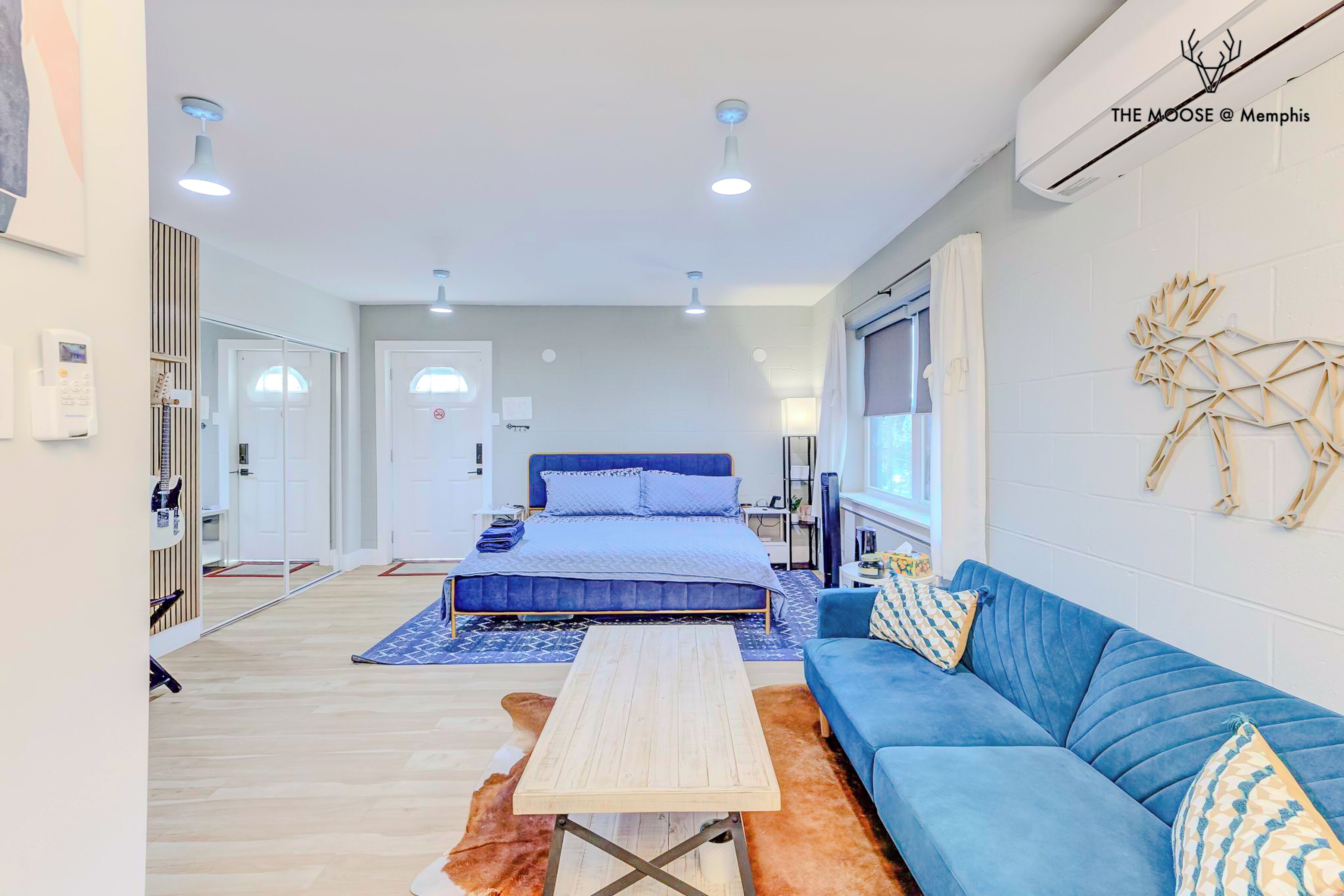A modern bedroom with a large bed, a blue sofa, and a wooden coffee table.