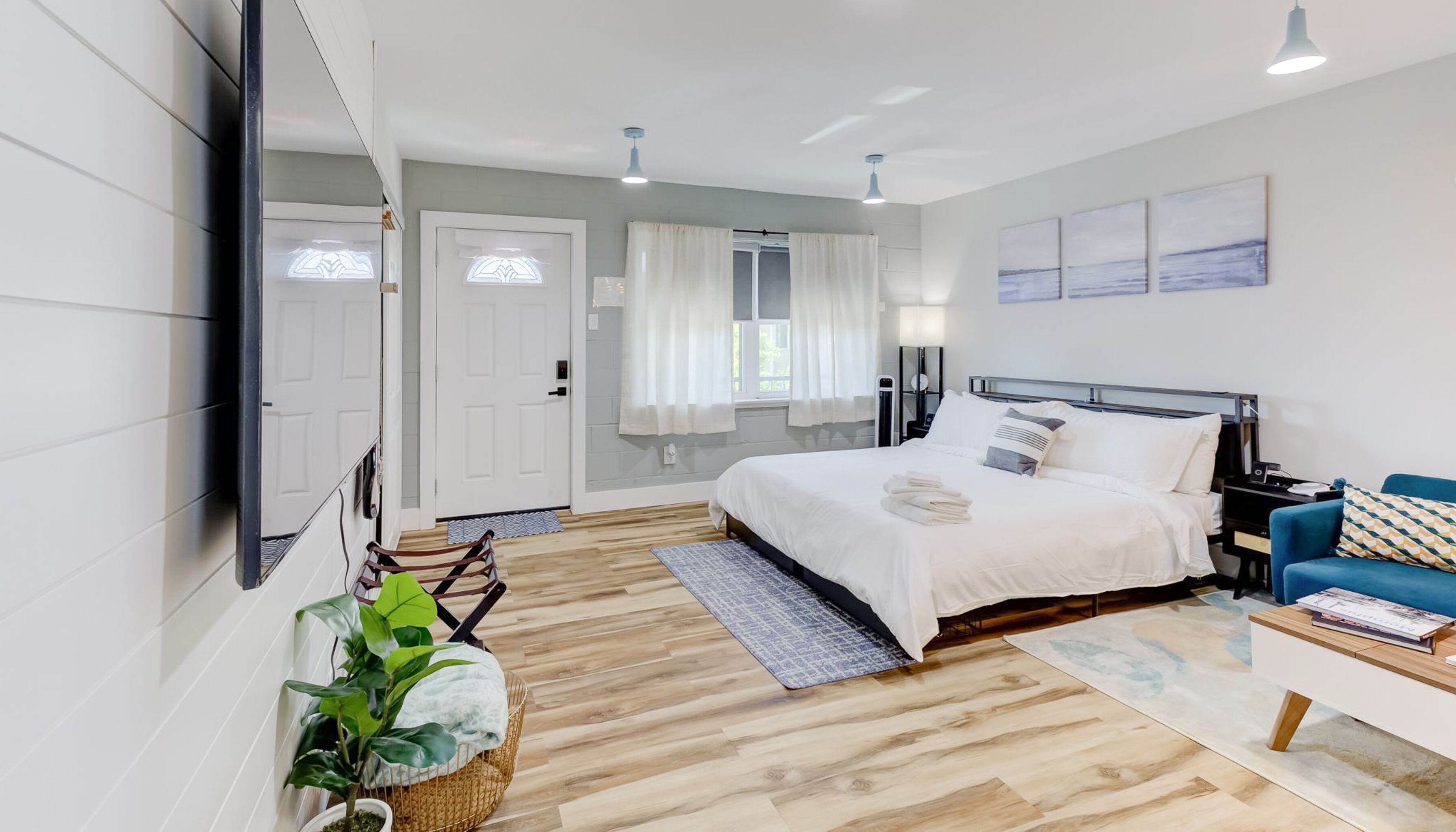 A modern bedroom with a large bed, a blue sofa, and a bedside table.