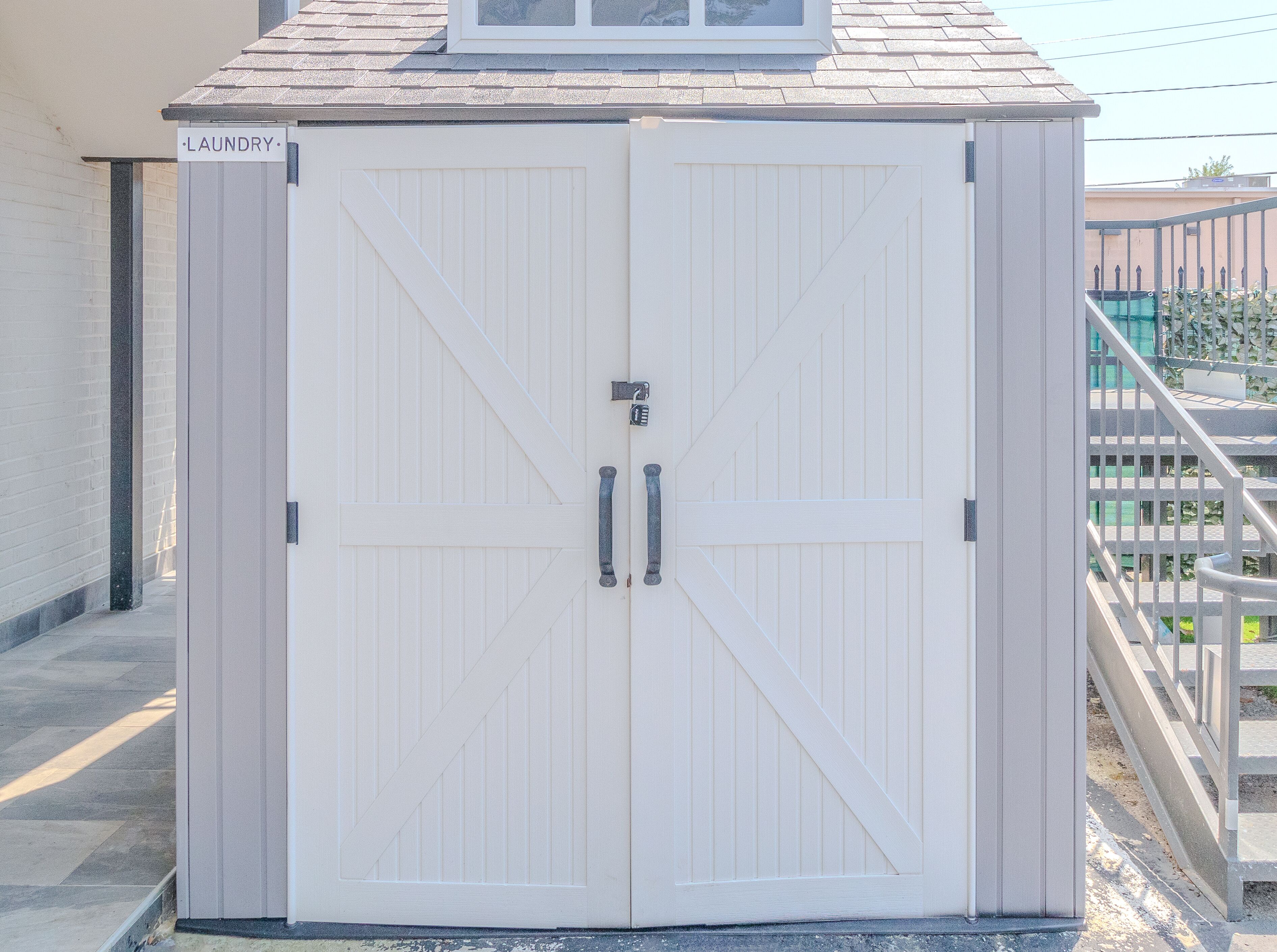 A white, double-door laundry room with a metal handle and a sign reading "LAUNDRY".