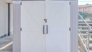A white, double-door laundry room with a metal handle and a sign reading "LAUNDRY".