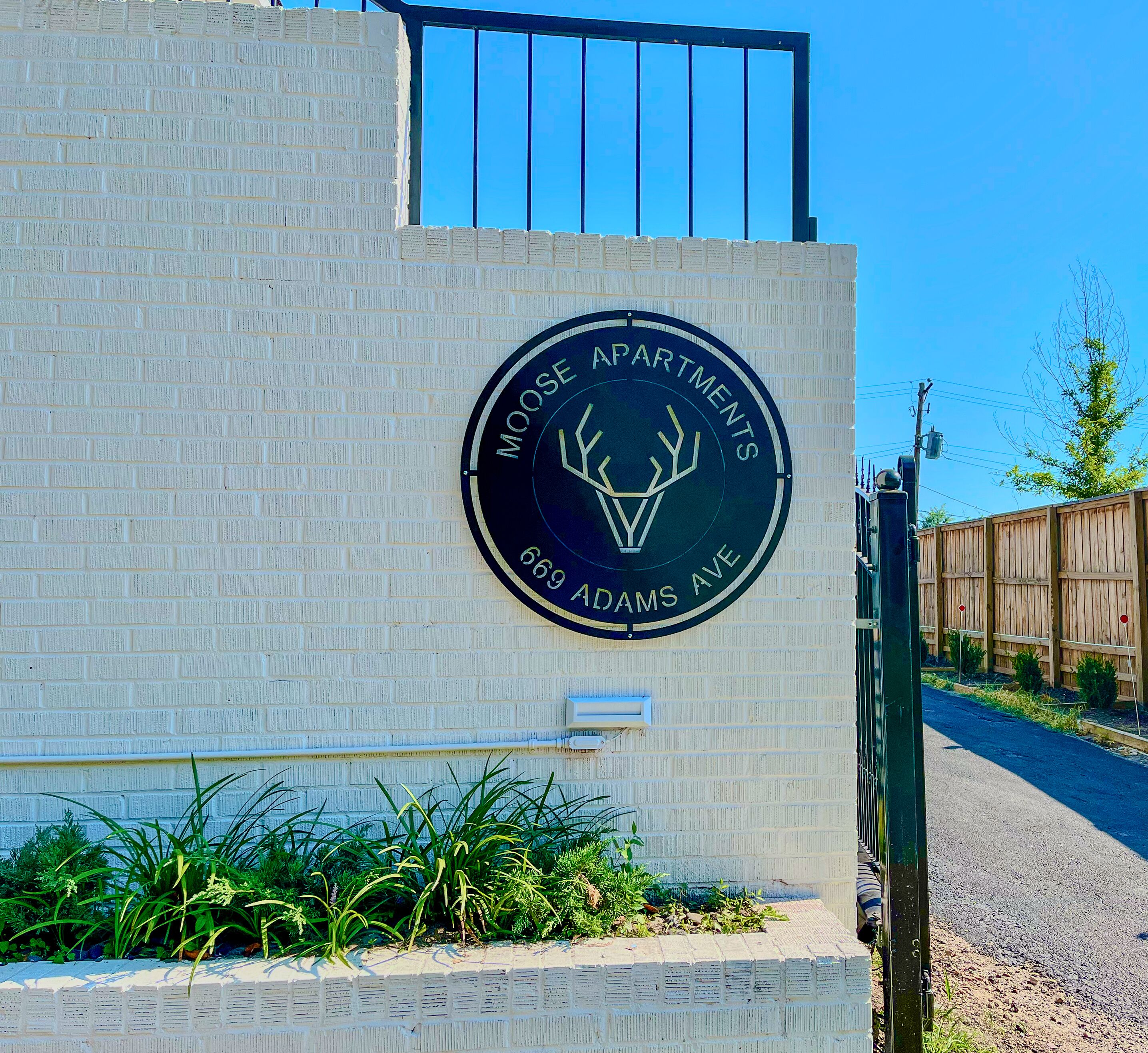Una señal circular con el logo de un alce y el texto Apartamentos Moose en Bro Adams Ave.