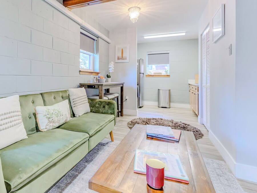 A cozy living room with a green sofa, a wooden coffee table, and a white brick wall.